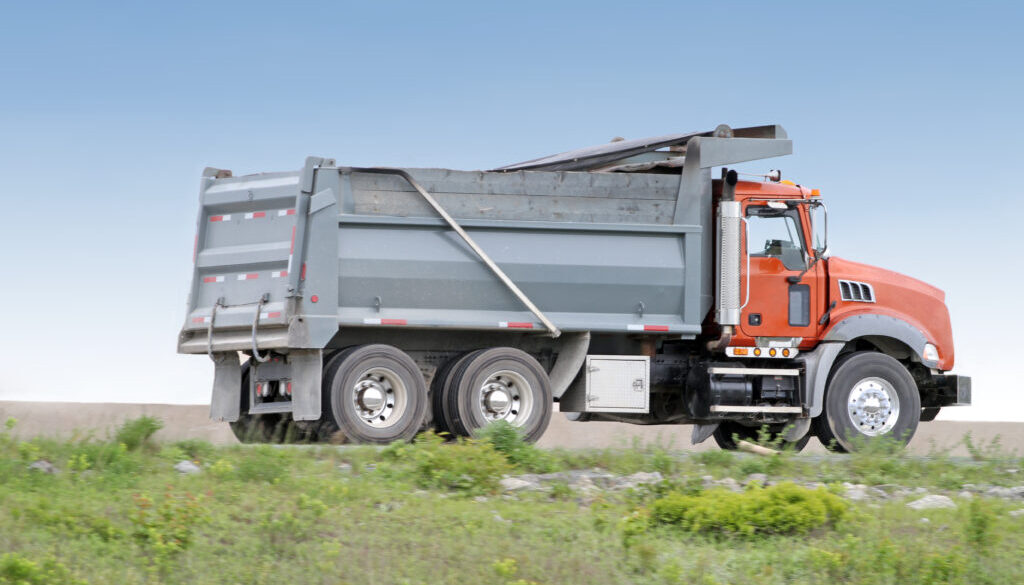 DumpTruckN - Complete Guide to Dump Trucks - Side view of a dump truck travelling a highway on its way to a construction site.