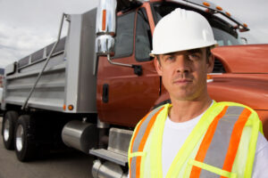 Dump Truck Owner Operator - Dump truck driver wearing safety hat in front of truck