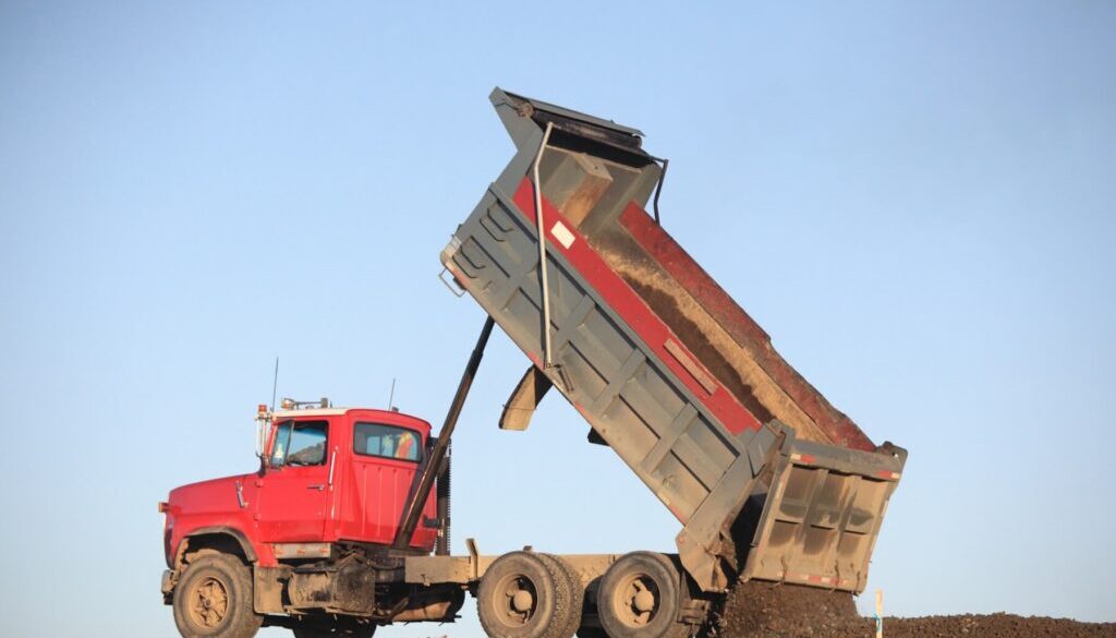 Red dump truck unloading dirt