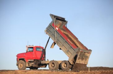 Red dump truck unloading dirt