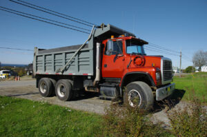Red dump truck parked on grass. Dump Truck Association