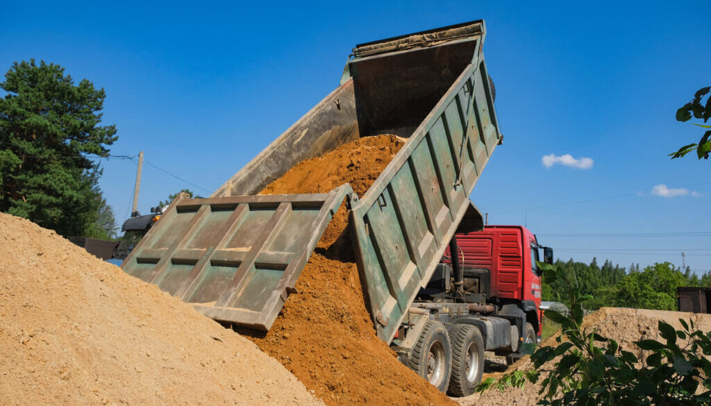 Dump truck unloading dirt at site. Dump Truck Business How Much Does It Cost to Start