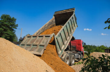 Dump truck unloading dirt at site. Dump Truck Business How Much Does It Cost to Start