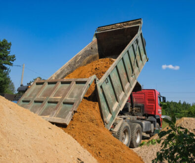Dump truck unloading dirt at site. Dump Truck Business How Much Does It Cost to Start