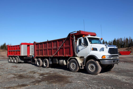 White dump truck on gravel site- How to Buy a Dump Truck